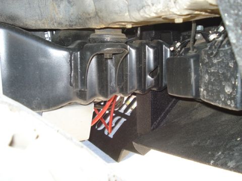 1987 Ford Bronco - Close-up view of vehicle undercarriage components, including wiring and brackets.
