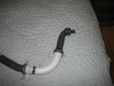 1996 Ford Thunderbird - A close-up view of a flexible automotive hose with metal connectors against a quilted background.