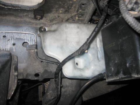 1996 Ford Thunderbird - Close-up of a vehicle's windshield washer fluid reservoir and associated hoses.