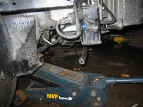1996 Ford Thunderbird - Vehicle undercarriage with hydraulic jack and exposed mechanical parts.