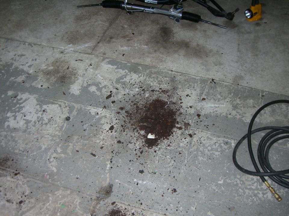 Steering rack and debris on concrete floor with Supermotors logo