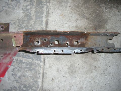 1988 Ford Bronco - Close-up of a heavily rusted metal frame section with numerous drilled holes.