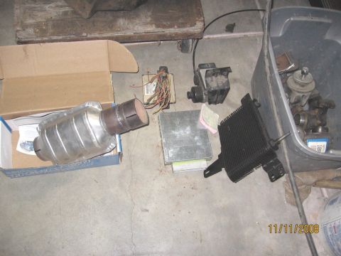 1994 Ford Bronco - Various automotive parts are displayed on the floor, including a catalytic converter and an oil cooler.