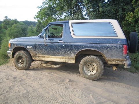 1990 Ford Bronco - This Ford Bronco is shown on a dirt path, with mud splattered on its body and tires.