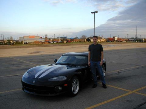 1996 Dodge Viper - A man poses with his black 1996 Dodge Viper, distinctive white racing stripes.