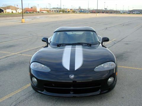 1996 Dodge Viper - A black 1996 Dodge Viper with dual white racing stripes is parked in a paved lot under a bright sky.