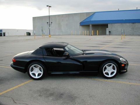 1996 Dodge Viper - A black Dodge Viper coupe is parked in an empty lot with a large building in the background.