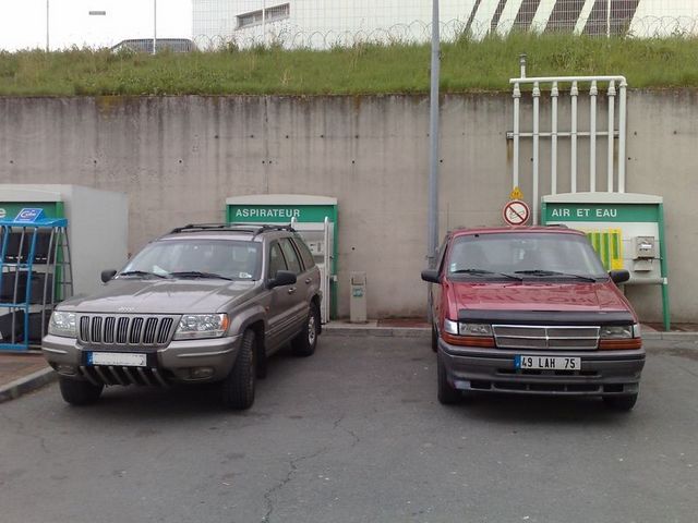Jeep Grand Cherokee and red minivan parked at air and water station