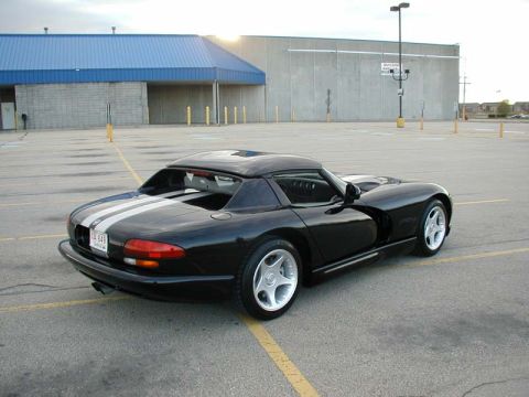 1996 Dodge Viper - A black 1996 Dodge Viper with dual white racing stripes is parked in an asphalt lot with a building in the background.