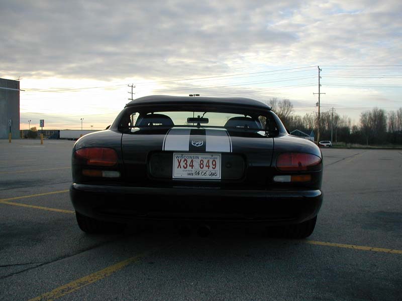Black Dodge Viper roadster rear view with white stripe and center exhaust at sunset