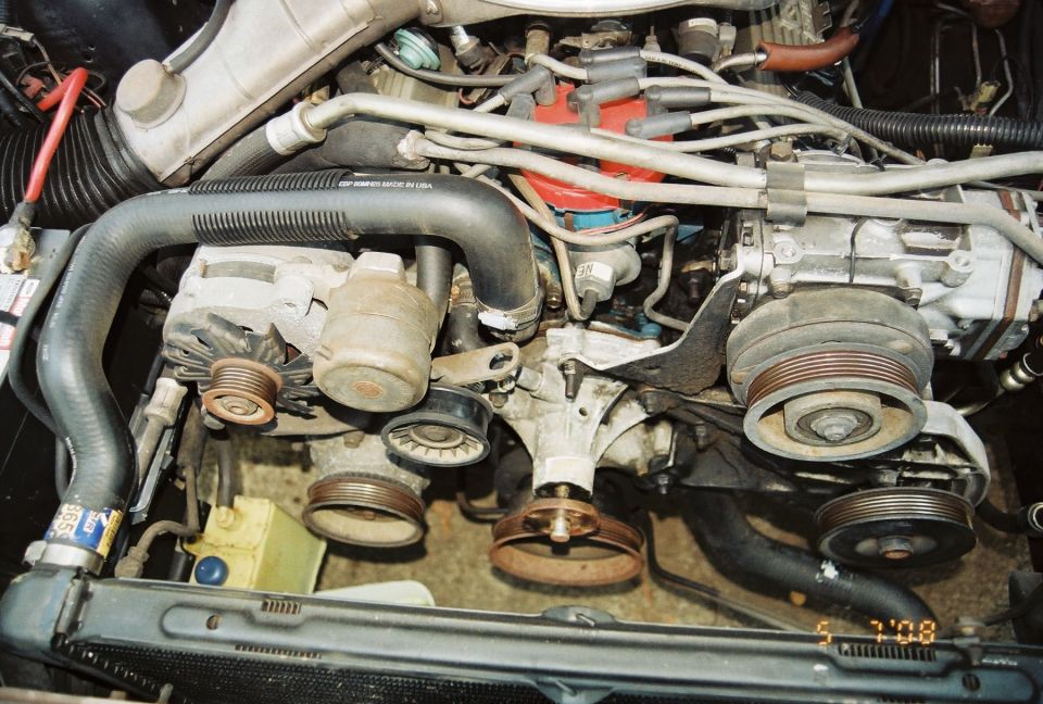 Engine bay with hoses, belts, alternator, and distributor cap visible