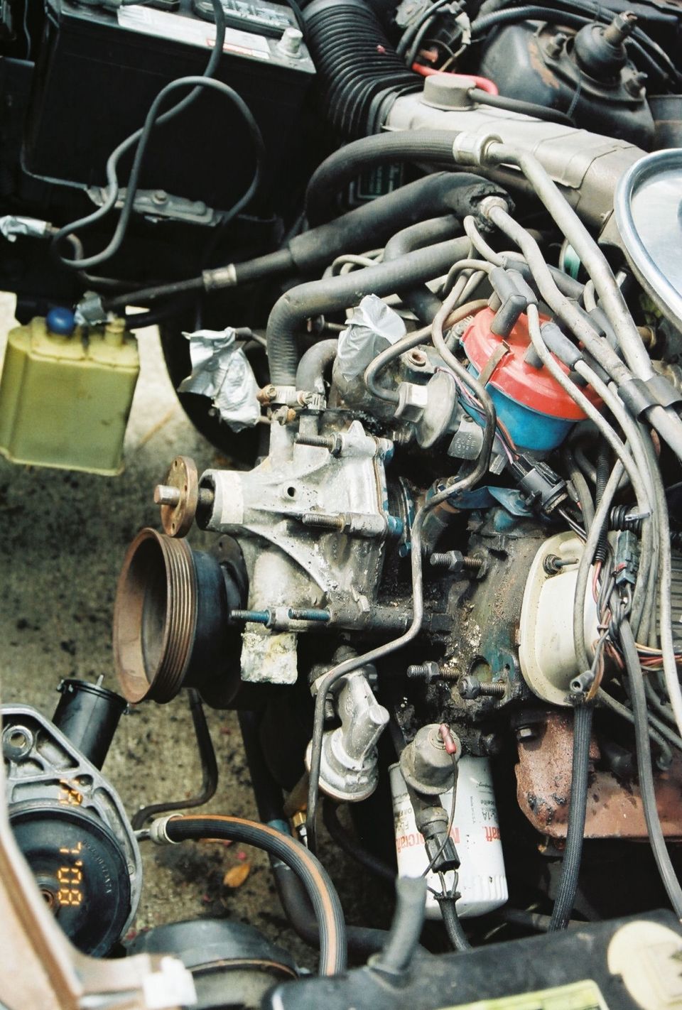 Engine bay with hoses, wires, distributor, oil filter, and a gauge showing 80.1