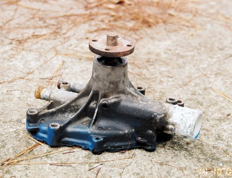 Used car water pump with blue and black paint, resting on concrete
