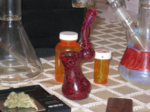 1996 Ford Crown Victoria - Drug paraphernalia and marijuana are arranged on a table with a scale and pill bottles.