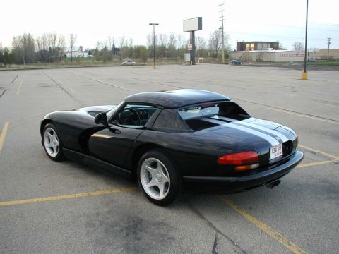 1996 Dodge Viper - A black 1996 Dodge Viper with dual white racing stripes is shown from the rear-left quarter angle in a parking lot.