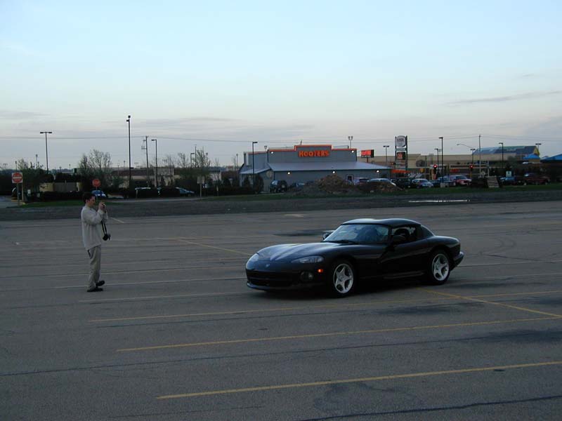 Black Dodge Viper RT/10 with hardtop parked in a large lot at dusk, photographer standing nearby