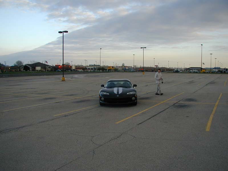 Black Dodge Viper GTS coupe with racing stripes, front view in an empty lot