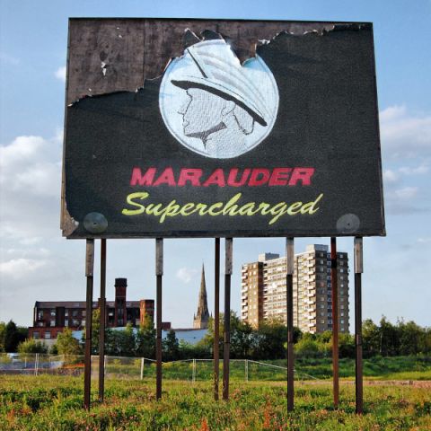 2003 Mercury Marauder - A damaged billboard advertises the 'Marauder Supercharged' with a profile logo, set in an outdoor scene.
