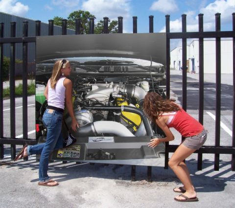 2003 Mercury Marauder - Two women examine an engine bay, which is displayed as a large print on a fence.