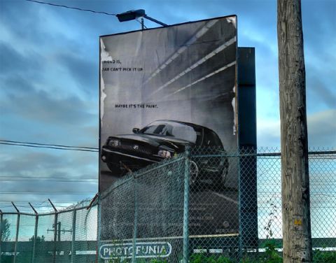 2003 Mercury Marauder - A billboard displays a black 2003 Mercury Marauder with the text 'MAYBE IT'S THE PAINT.'