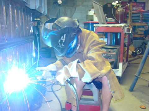 1948 Jeep Wrangler - A person is welding in a workshop, with tools and equipment visible in the background.