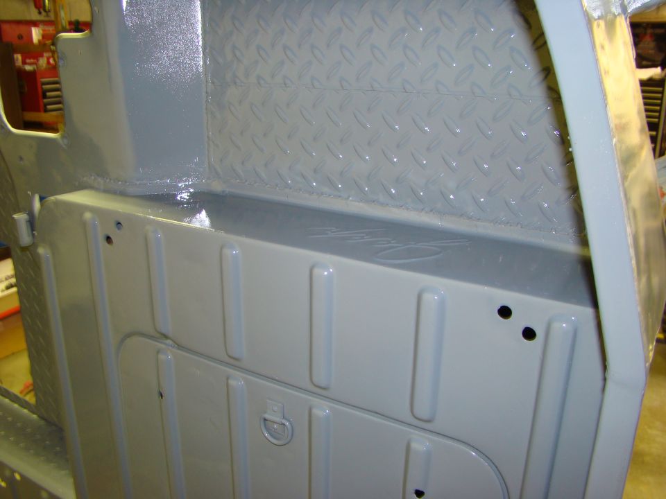 Close-up of gray painted interior of a Jeep CJ, showing diamond plate on the rear wall and ribbed panels on the side