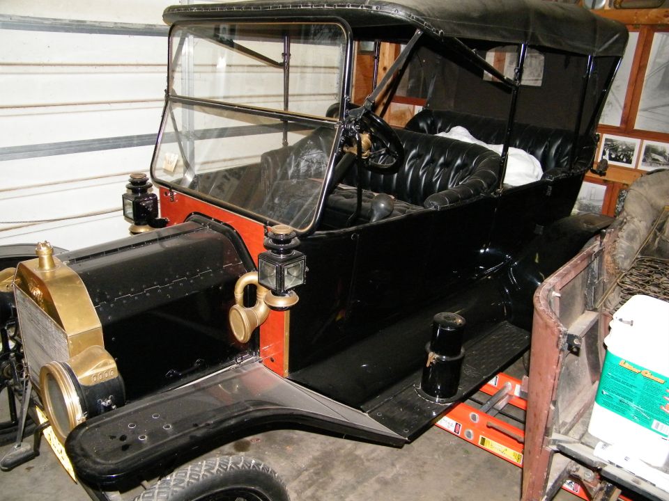 Black antique touring car with brass radiator in a garage