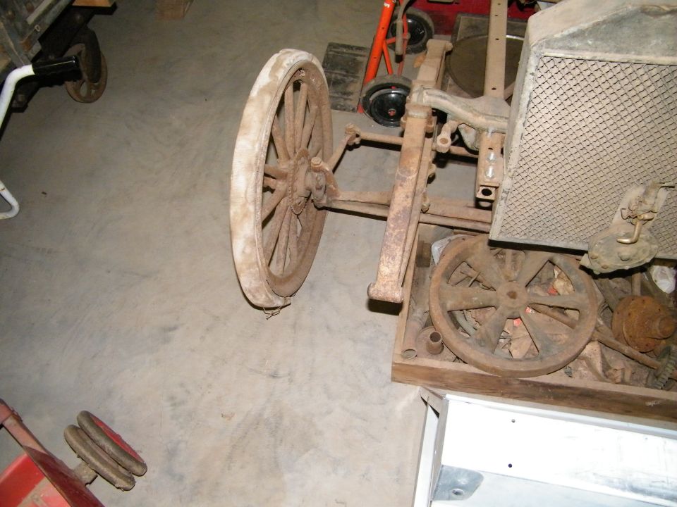 Antique vehicle chassis with wooden-spoke wheel in a shop