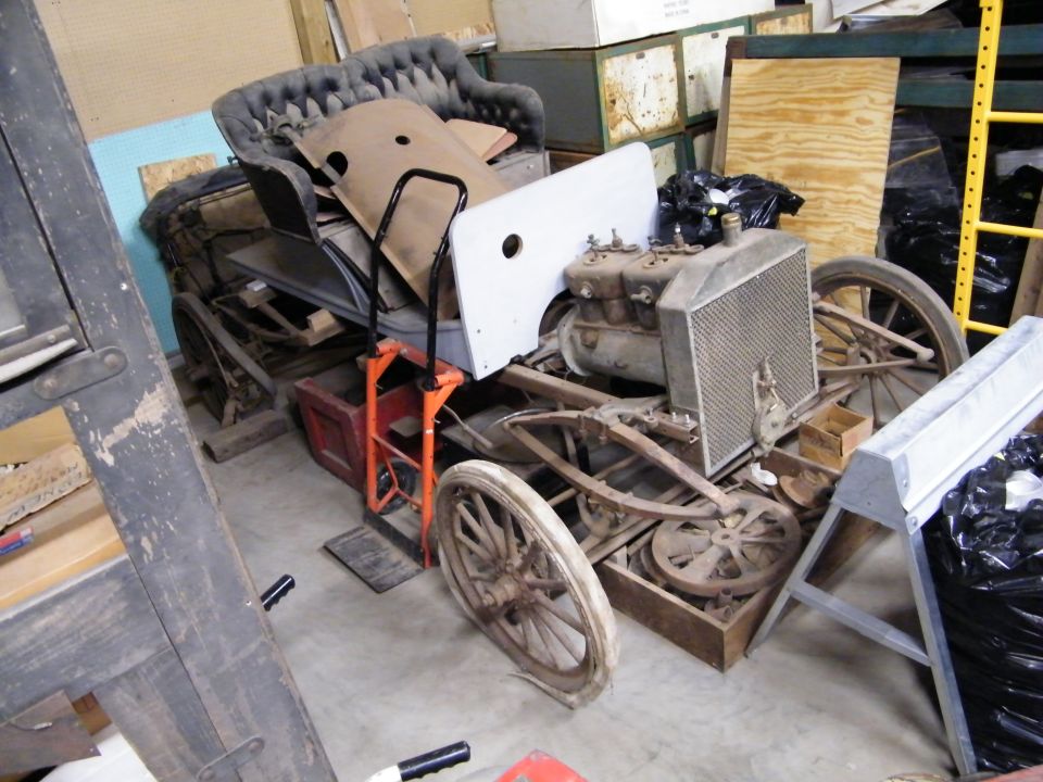 Disassembled antique car frame and body in a workshop