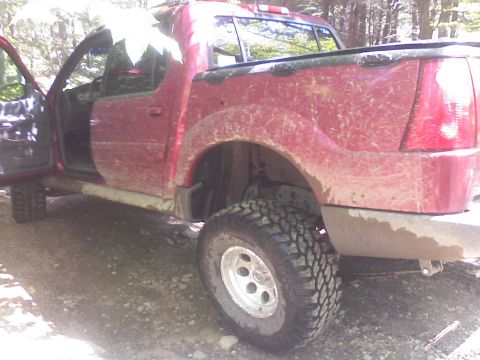 2001 Ford Explorer - This red pickup truck, seen from the side with its doors open, appears to be equipped for off-road use with its large tires.
