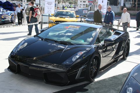 1998 Ford Crown Victoria - A black Lamborghini Gallardo is displayed at an outdoor event, with other vehicles and people in the background.