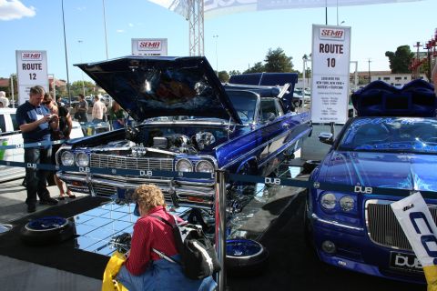 1998 Ford Crown Victoria - Customized lowrider cars displayed at a SEMA event, with signage for Route 10 and 12.