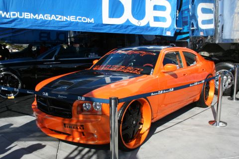 1998 Ford Crown Victoria - An orange Dodge Charger with custom rims and a black hood is displayed under a DUB Magazine banner.