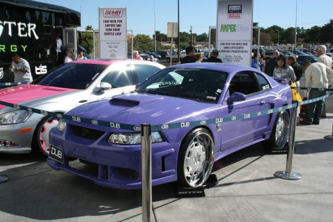 1998 Ford Crown Victoria - A custom purple Ford Mustang is displayed at an event, with a silver car and a Monster Energy truck in the background.