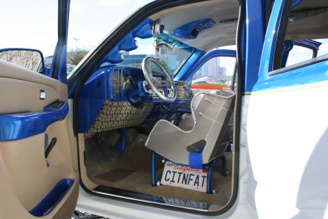 1998 Ford Crown Victoria - The interior of a truck features custom blue paint, a racing seat, and a personalized license plate.