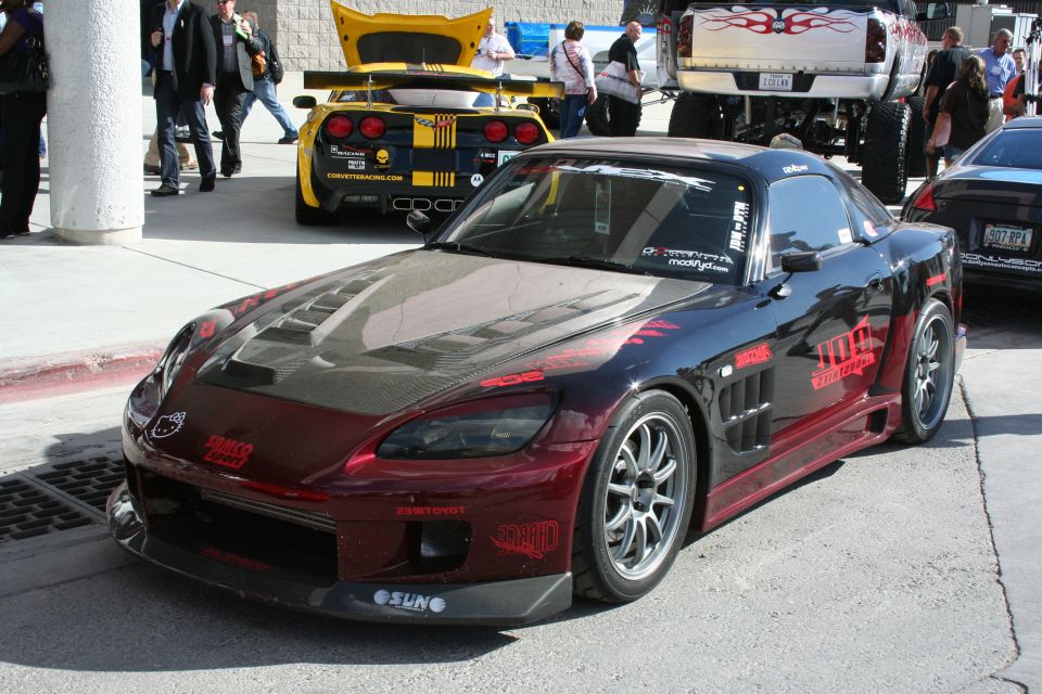 Modified black and red sports car with a carbon fiber hood, custom body kit, and racing decals