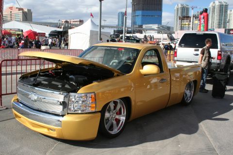1998 Ford Crown Victoria - A custom yellow pickup truck is displayed with its hood open, its lowered stance and chrome accents.