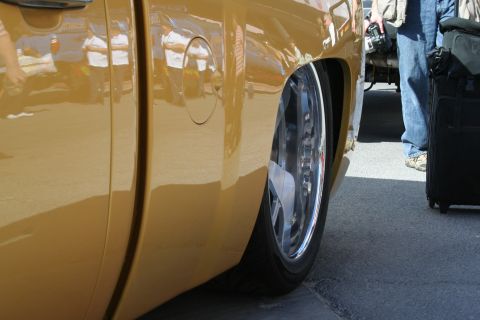 1998 Ford Crown Victoria - Close-up of a gold pickup truck's rear wheel and lowered suspension, showing custom chrome rims.