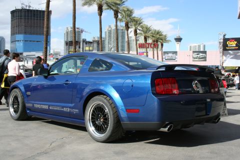 1998 Ford Crown Victoria - Blue Ford Mustang with custom wheels and spoiler is parked outdoors. Text on the side reads TOYO TIRES.