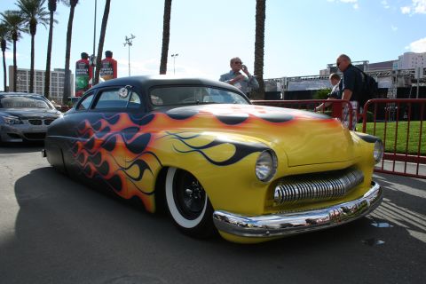 1998 Ford Crown Victoria - A heavily customized vintage car with a striking flame paint job and lowered suspension is on display.