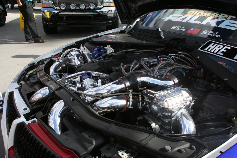 Engine bay with twin turbochargers and chrome piping. HRE logo visible