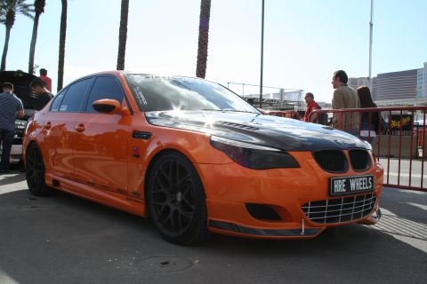 1998 Ford Crown Victoria - A modified orange BMW sedan is parked outdoors with people in the background.
