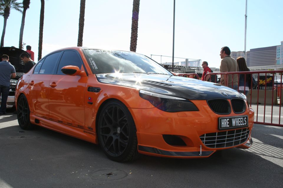 Orange BMW sedan with black hood and black wheels. License plate says HRE WHEELS