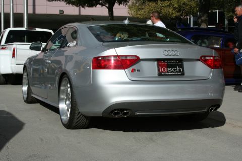 1998 Ford Crown Victoria - Rear view of a silver Audi S5 coupe with a custom license plate and dual exhaust pipes, parked outdoors.