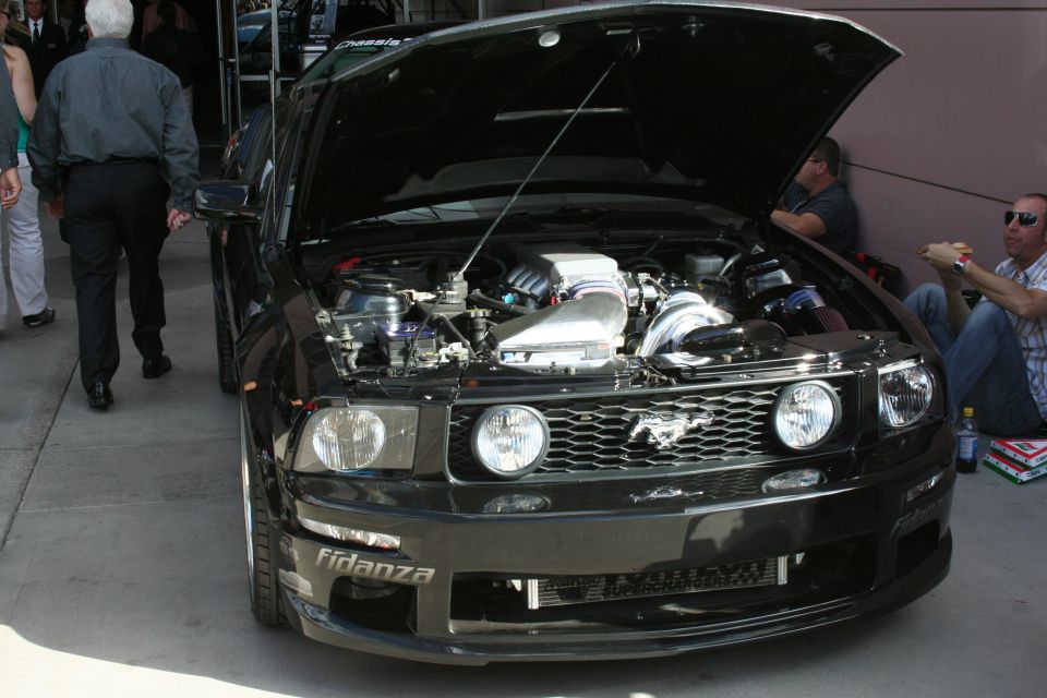 Black Ford Mustang with hood open showing engine, fidanza and supercharger text visible