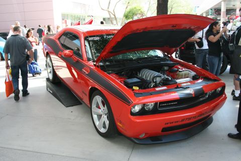 1998 Ford Crown Victoria - A red Dodge Challenger with black racing stripes is displayed with its hood open, revealing the engine.