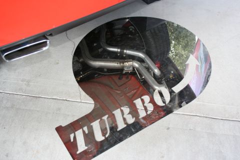 1998 Ford Crown Victoria - The underside of a vehicle shows its exhaust system, with a "Turbo" graphic visible on the pavement below surface below surface below surfa…