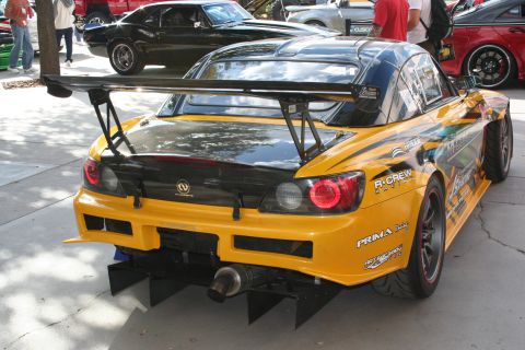 1998 Ford Crown Victoria - A modified yellow sports car with a prominent rear wing and racing livery is parked outdoors.