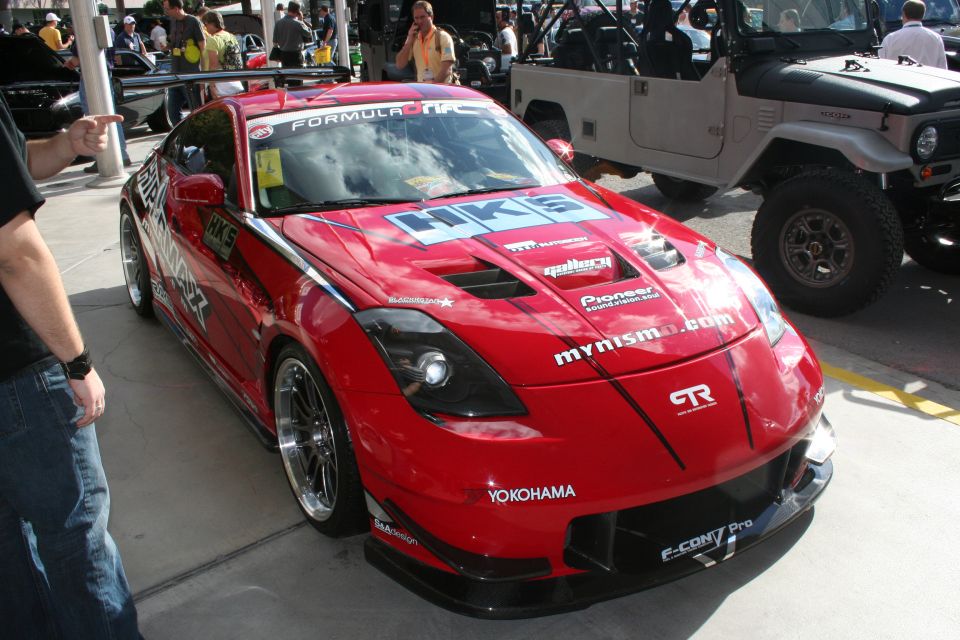 Red sports car with HKS and Yokohama decals, parked next to a tan off-road vehicle