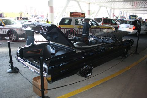 1998 Ford Crown Victoria - A black convertible is displayed with its trunk and hood open, surrounded by other vehicles.